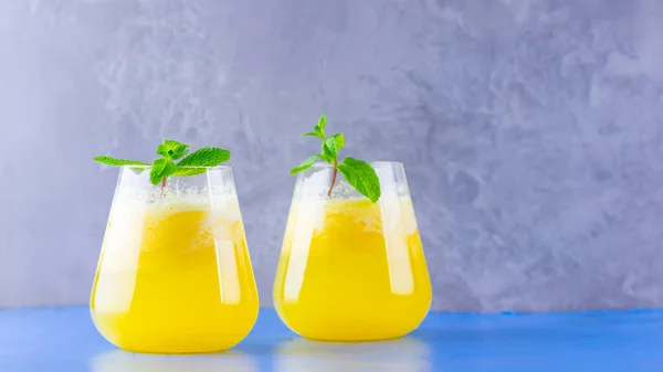 Pineapple juice on a blue gray background. Juice for detox in the glass. Pineapple smoothie with fresh pineapple. Summer drink with mint