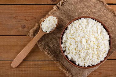 Çuval bezinde süzme peynir. Kâsede taze süzme peynir. Tahtada yumuşak peynir ve tahta kaşık. Üst Manzara. Boşluğu kopyala