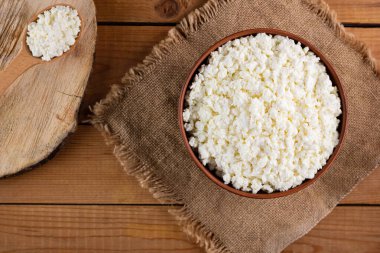 Çuval bezinde süzme peynir. Kâsede taze süzme peynir. Tahtada yumuşak peynir ve tahta kaşık. Üst Manzara. Boşluğu kopyala