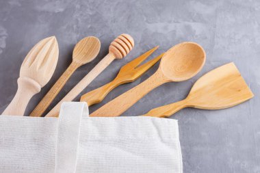 Sıfır atık. Pamuk eko çanta ve gri arka planda ahşap çatal bıçak takımı. Çevre dostu ahşap çatal bıçak takımı. Plastiksiz konsept. Minimalizm. Üst Manzara. Boşluğu kopyala