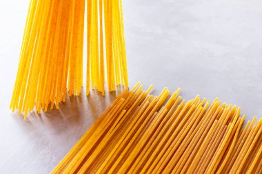Gri arka planda sarı makarna. Çimento arka planında spagetti. Çiğ spagetti bolonez. Yemek geçmişi konsepti. Üst görünüm