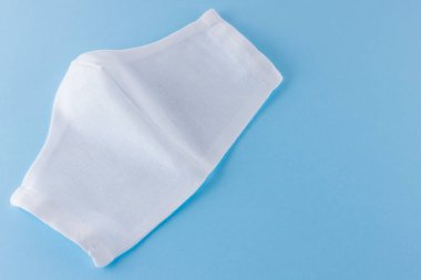 Beyaz antivirüs maskesi. Mavi arka planda koruyucu gazlı bez maskesi. Pamuktan yapılmış el yapımı tıbbi maske. Gazlı bezden yapılmış koruyucu yüz maskesi. Üst Manzara. Boşluğu kopyala