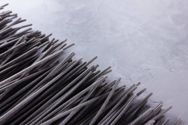 Gri arka planda siyah makarna. Çimento arka planında siyah spagetti. Mürekkepbalıklı çiğ spagetti. Yemek geçmişi konsepti. Üst Manzara. Boşluğu kopyala