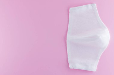 Pembe arka planda koruyucu gazlı bez maskesi. Beyaz antivirüs maskesi. Pamuktan yapılmış el yapımı tıbbi maske. Gazlı bezden yapılmış koruyucu yüz maskesi. Üst Manzara. Boşluğu Kopyala