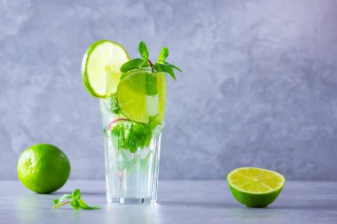 Limonlu mojito kokteyli ve uzun bardakta nane şekeri. Gri arka planda camlı taze mojito. Naneli kokteyli limonla tazeliyorum. Kaynamış su. Boşluğu kopyala