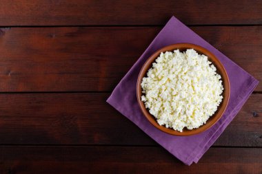 Ahşap tahtalardaki süzme peynir. Seramik kasede taze süzme peynir. Keten peçetede yumuşak peynirli kil tabağı. Üst Manzara. Boşluğu kopyala