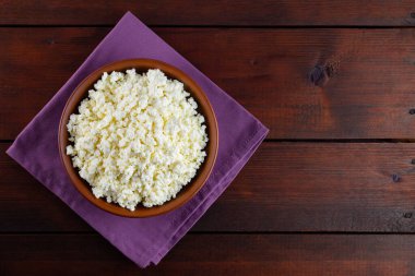 Ahşap tahtalardaki süzme peynir. Seramik kasede taze süzme peynir. Keten peçetede yumuşak peynirli kil tabağı. Üst Manzara. Boşluğu kopyala
