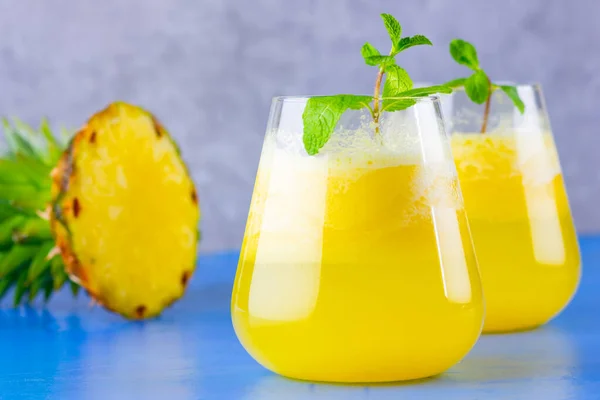 Pineapple cocktail on a blue gray background. Cold pineapple cocktail with mint. Summer tropical cocktail. Healthy drink