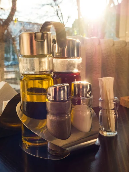 salt shaker, pepper shaker, bottles with olive oil and balsamic vinegar in a stand, toothpicks on a table in a cafe