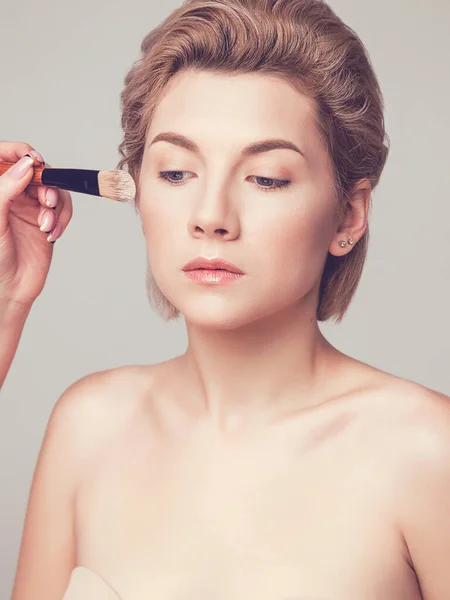 applying foundation on a woman\'s face. Makeup artist training concept. Studio shot, close-up, skin retouching