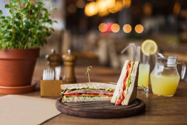 Büyük bir iştah açıcı jambon, domates, marul, peynir Restaurant'ta ahşap plaka üzerinde sandviçle