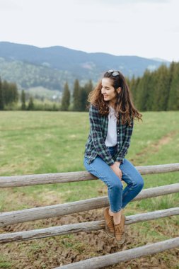 Dağlarda ahşap çit oturan güzel kadın. Dağlarında seyahat. 