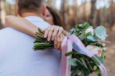 Kadın ve erkekte orman. Gelin kocası sarılmak. Bir buket çiçek tutan gelin. İki sevgili. Düğün.