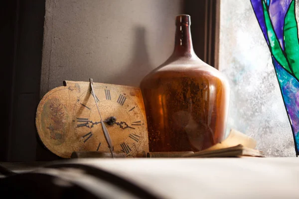 Reloj antiguo y la vieja botella cerca de una pared de la ventana — Foto de Stock
