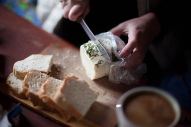Genç adam kesme peyniri ahşap masa üzerinde olduğunu.