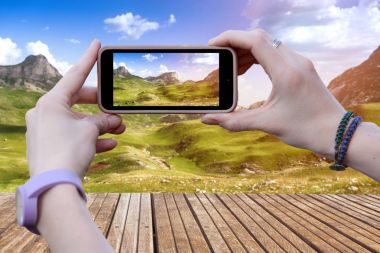 Bir kadın bir cep telefonu bir güzel dağ manzarası resimleri alma.