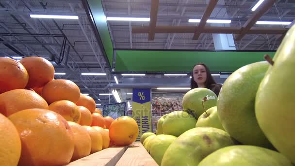 Mujer joven elige naranja en la cámara store.slow — Vídeo de stock