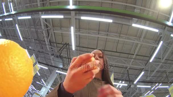 Mujer joven elige naranja en la cámara store.slow — Vídeos de Stock