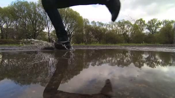 Człowiek działa przez kałuże w parku. Zbliżenie stóp. zwolnionym tempie — Wideo stockowe