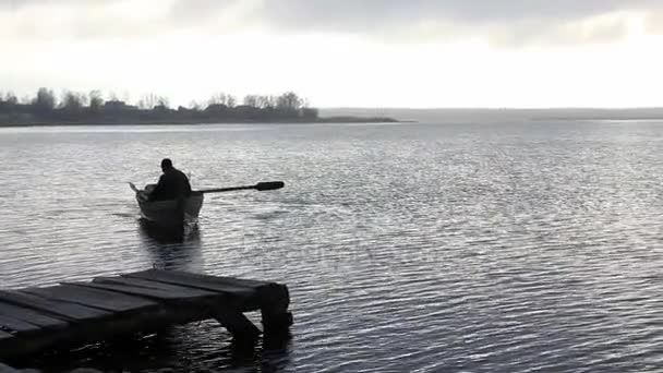 Fisherman swims on an old boat to the stony bank at dusk — Stock Footage Fisherman swims on an old boat to the stony bank at dusk Video Clip