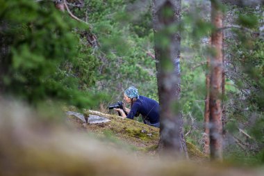 Genç bir kadın, sonbahar ormanında kamerayla fotoğraf çekiyor.