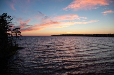 Kuzey deniz manzarası göl Onega Gölü üzerinde-batan güneşin ışınlarını yansıtan granit kıyıya dalgalar yendi.