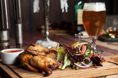 Ahşap oyun tahtası sebzeli tavuk. yanında bir bardak hafif bira. Restoran, geleneksel mutfağı