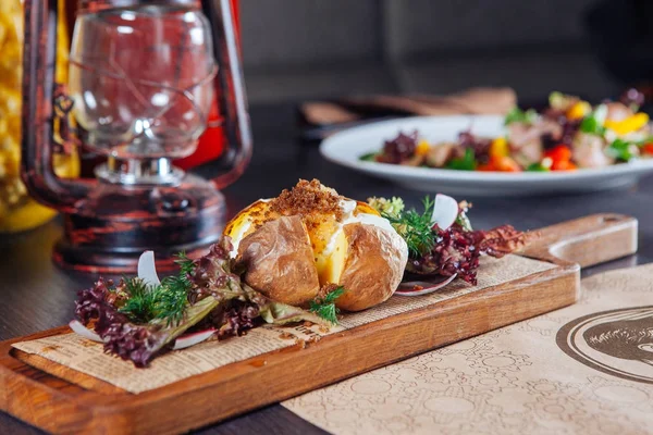 Patatas asadas con hierbas en una tabla de madera sobre la mesa en el restaurante. estilo country — Foto de Stock