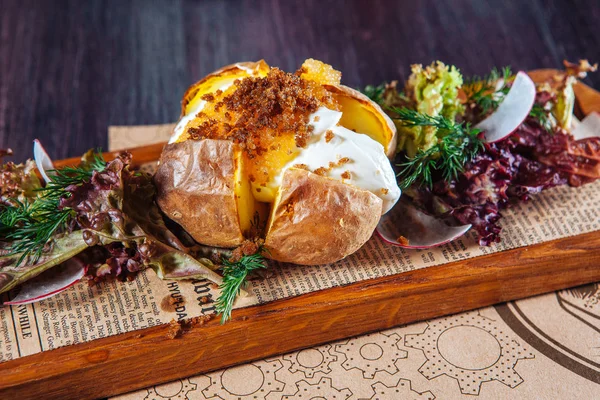 Patatas asadas con hierbas en una tabla de madera sobre la mesa en el restaurante. estilo country — Foto de Stock