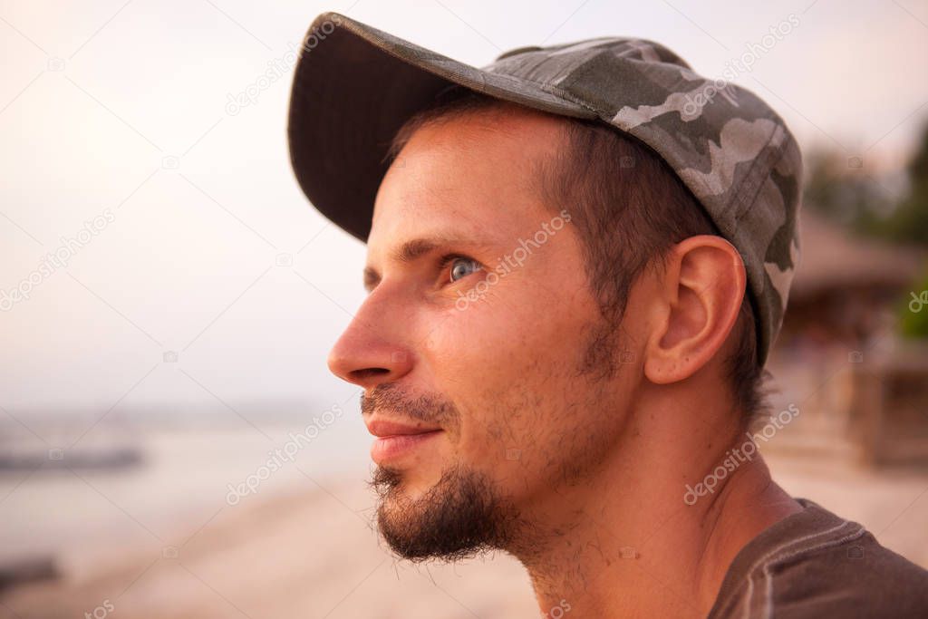 Portrait of a dreamy young man on the ocean in a warm summer day at sunset