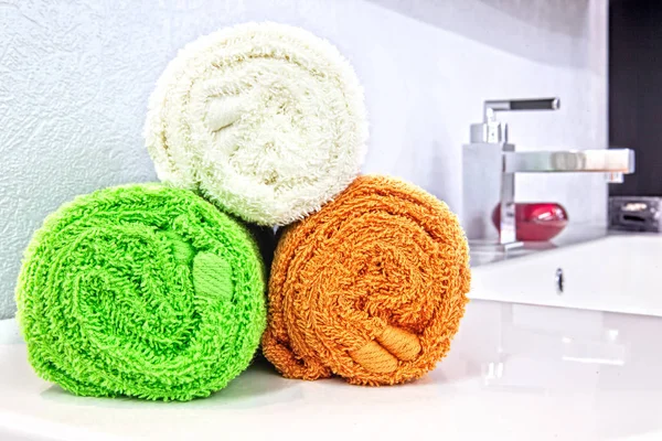 Rolled fresh towels on table in bathroom — Stock Photo, Image