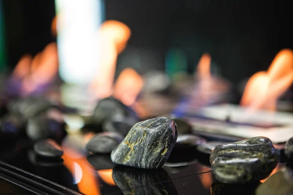 Bioethanol fueled portable fireplace burning at home, for live fire at home, no chimney and mantelpiece is needed. Liquid bio ethanol burns in cup. Round shaped glasses with stones inside. Stones — Stock Image Bioethanol fueled portable fireplace burning at home, for live fire at home, no chimney and mantelpiece is needed. Liquid bio ethanol burns in cup. Round shaped glasses with stones inside. Stones Stock Picture