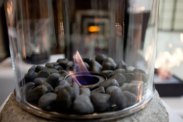 Bio-ethanol aangewakkerd draagbare open haard branden thuis, voor live vuur thuis, geen schoorsteen en schoorsteen nodig is. Vloeibare bio-ethanol brandt in een kopje. Rond glas met stenen binnenin — Stockfoto