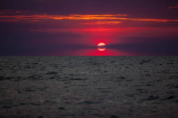 Hermosa puesta de sol roja y naranja sobre el mar en un cielo nublado. El sol se pone sobre el mar. Dos gaviotas están volando contra la puesta del sol. Cielo dramático puesta del sol — Foto de Stock
