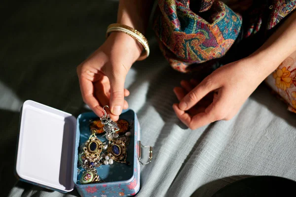 Kobieta w domu bada piękną dekorację w pudełku z biżuterią, ręce zbliżenie — Zdjęcie stockowe