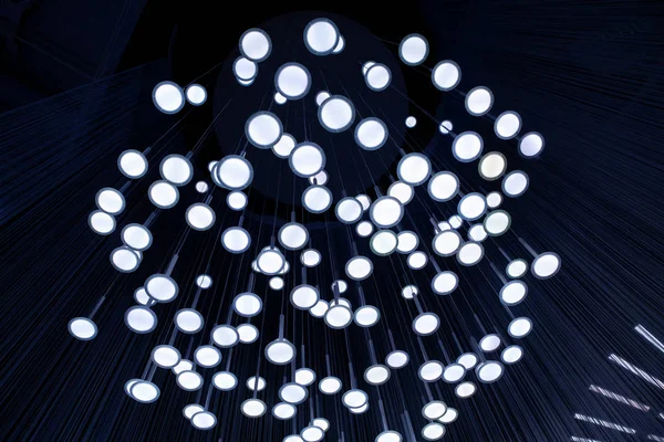 Many light bulbs that go down with their cables from the ceiling creating a unique optical illusion. — Stock Photo, Image