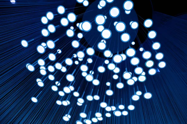 Many light bulbs that go down with their cables from the ceiling creating a unique optical illusion.
