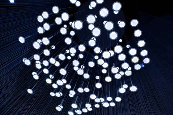 Many light bulbs that go down with their cables from the ceiling creating a unique optical illusion. modern lighting in the interior — Stock Photo, Image