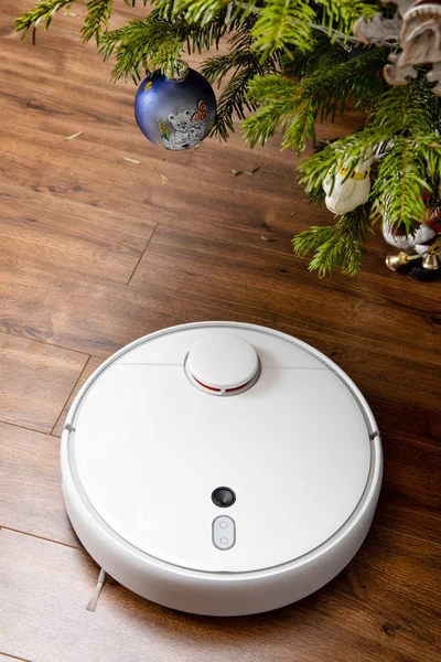 Aspiradora robot limpia bajo el árbol de Navidad. el concepto del hogar inteligente — Foto de Stock