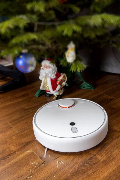 Aspiradora robot limpia bajo el árbol de Navidad. el concepto del hogar inteligente — Foto de Stock