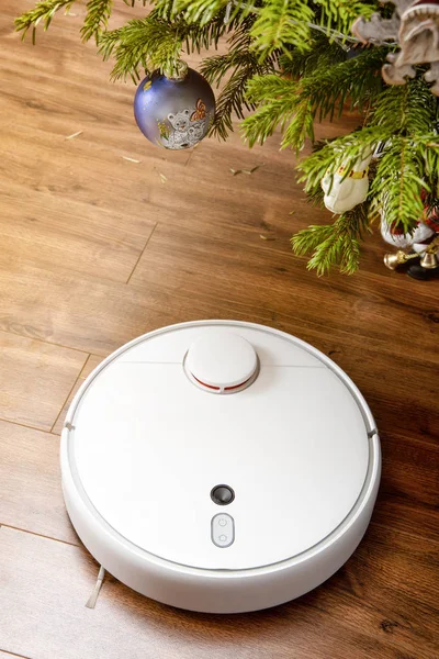 Aspiradora robot limpia bajo el árbol de Navidad. el concepto del hogar inteligente — Foto de Stock