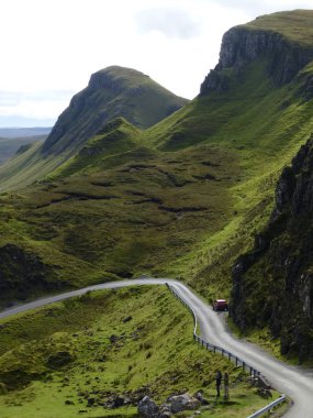 Twisting road down from the Quiraing, Isle of Skye, with autumn sunshine highlighting the contours of the mountain ridge