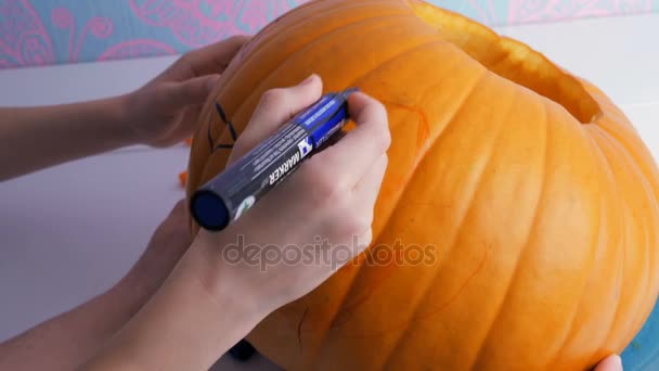 Familia preparándose para Halloween. Dibujar una cara de demonio en una calabaza con un marcador — Vídeo de stock