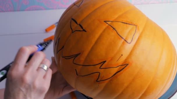 Family preparing for Halloween. Drawing a demon face on a pumpkin with a marker — Stock Video