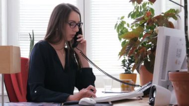 Bilgisayarda çalışarak ve çağrı merkezi telefonda konuşurken kadın resepsiyonist
