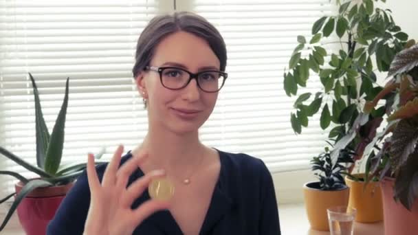 Young woman shows a golden litecoin in hand at camera. — Stock Video