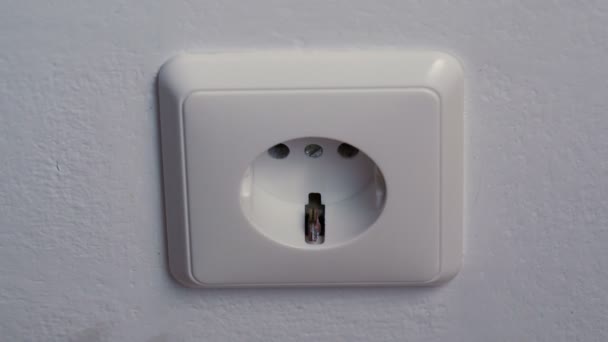 Hand puts a power plug in the wall socket — Stock Video