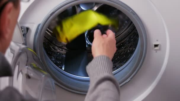 Un homme met une chemise de football d'un enfant dans la machine à laver — Video