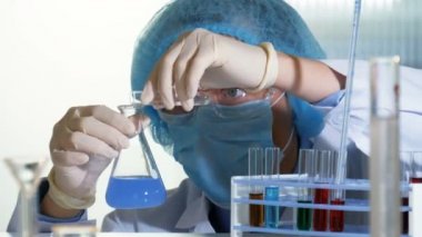 Araştırmacı test tüpü kimyasallardan bir şişesi dökülen yoğun kimyasal reaksiyon tetikliyor