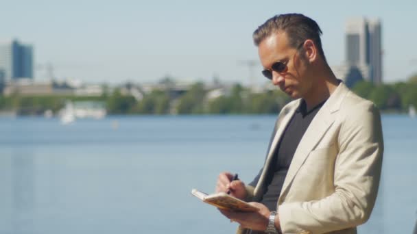 Ein entspannter Manager macht sich nach Feierabend Notizen in seinem Tagebuch — Stockvideo
